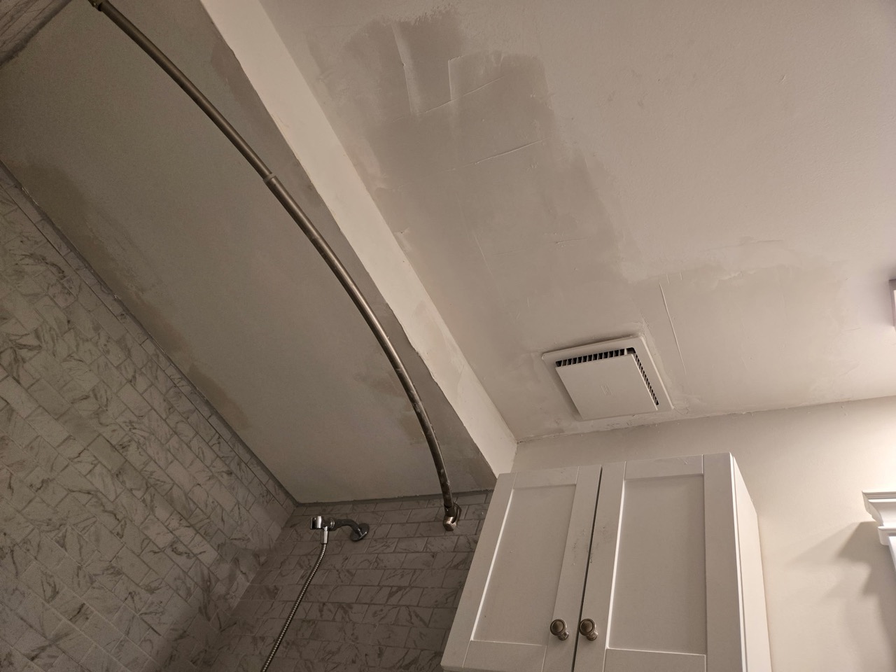 Bathroom ceiling with patching compound visible around the shower area and vent