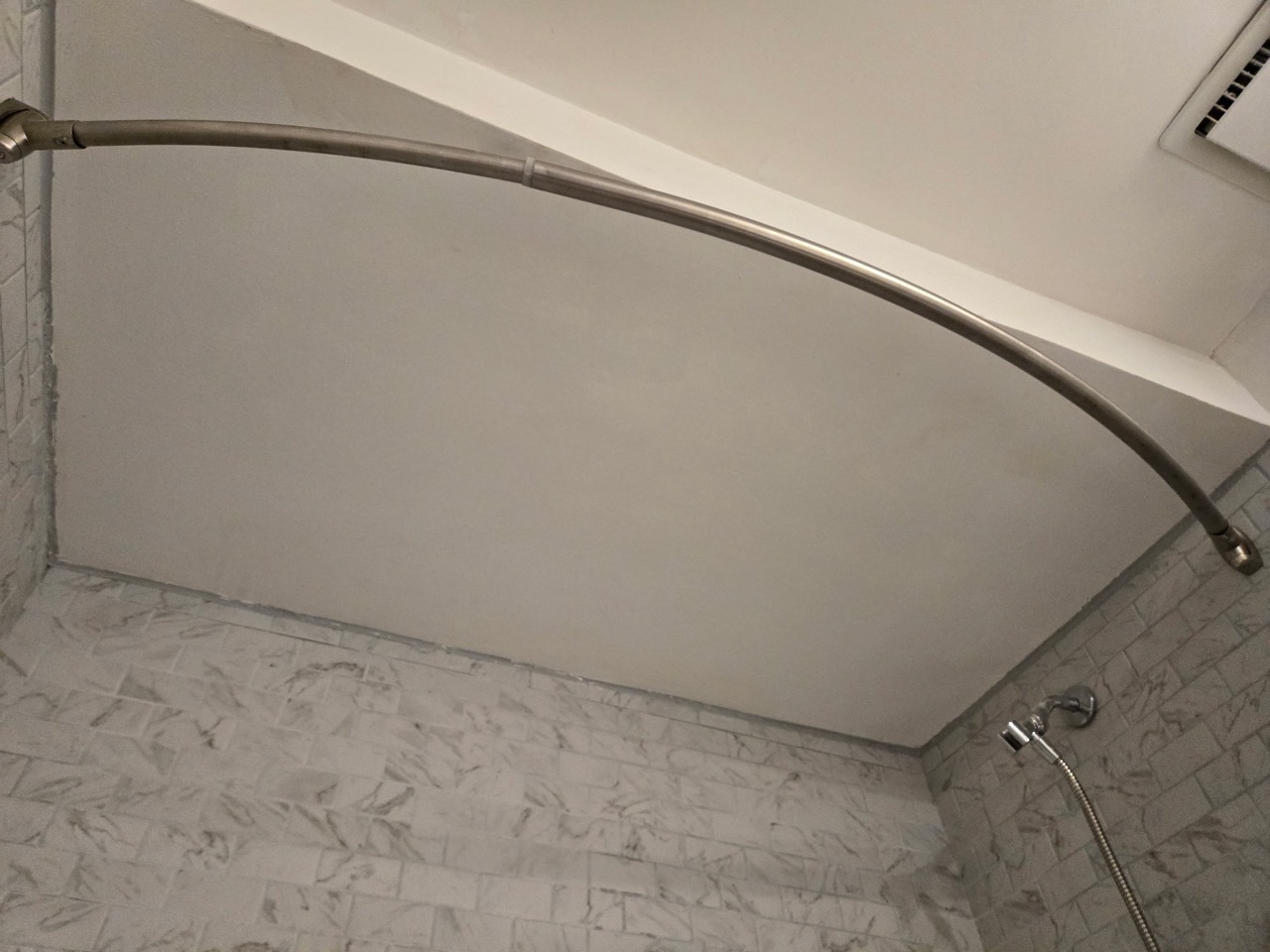 Bathroom ceiling above a curved shower rail following patching work