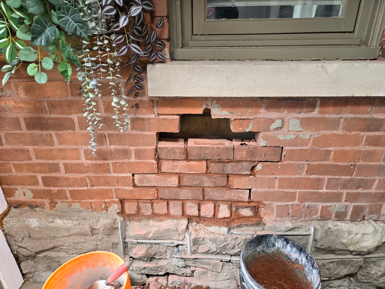 Open section of brickwork beneath a window during preparation for repair