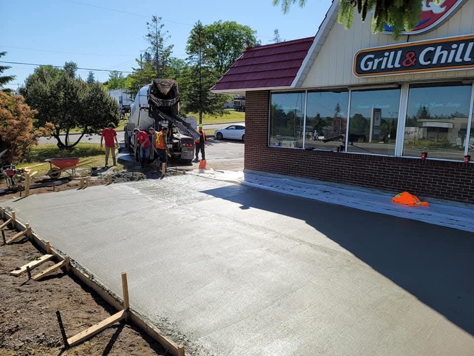 Worker beside a fresh concrete walkway outside a commercial building