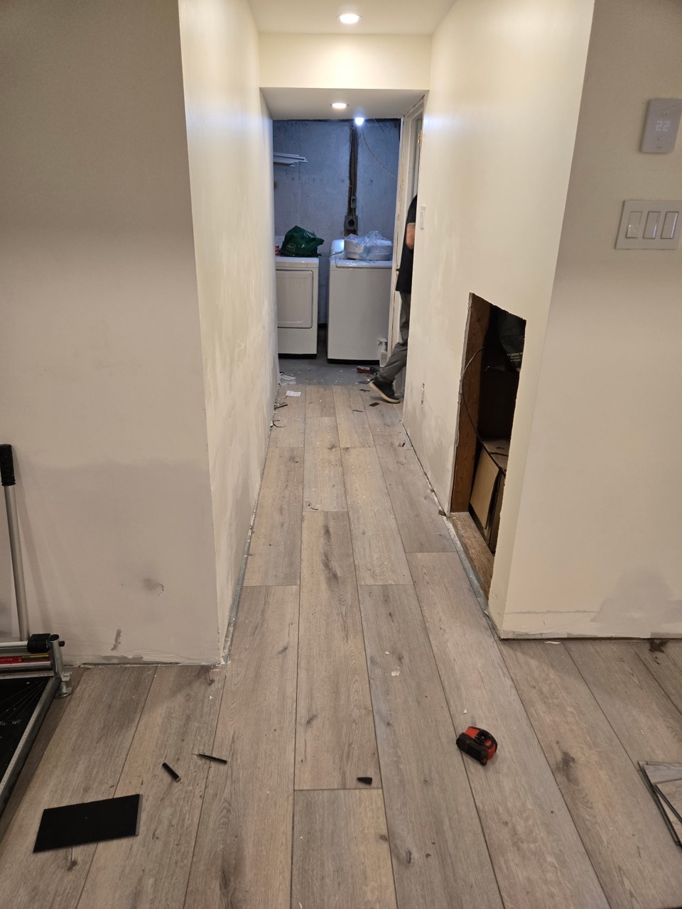 Grey plank flooring continuing along a hallway toward a bathroom during renovation