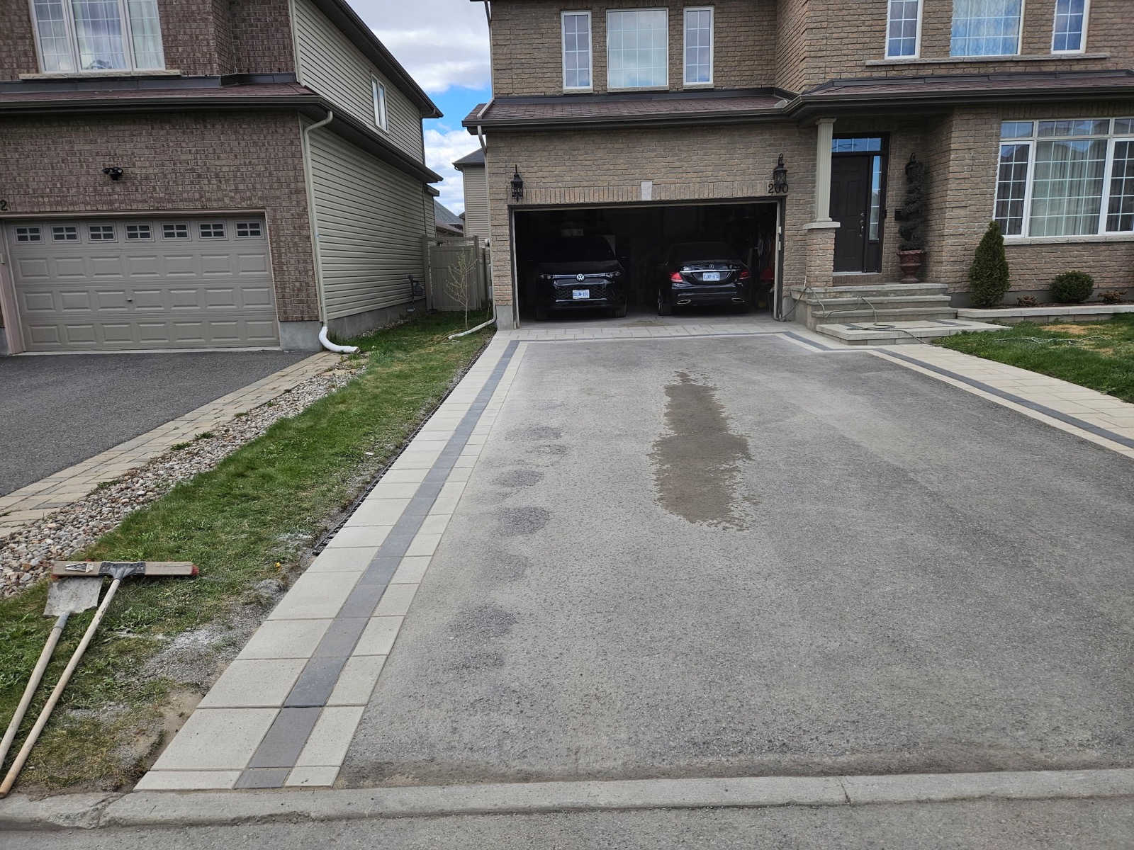 Driveway framed by light pavers and a contrasting dark border leading to a double garage