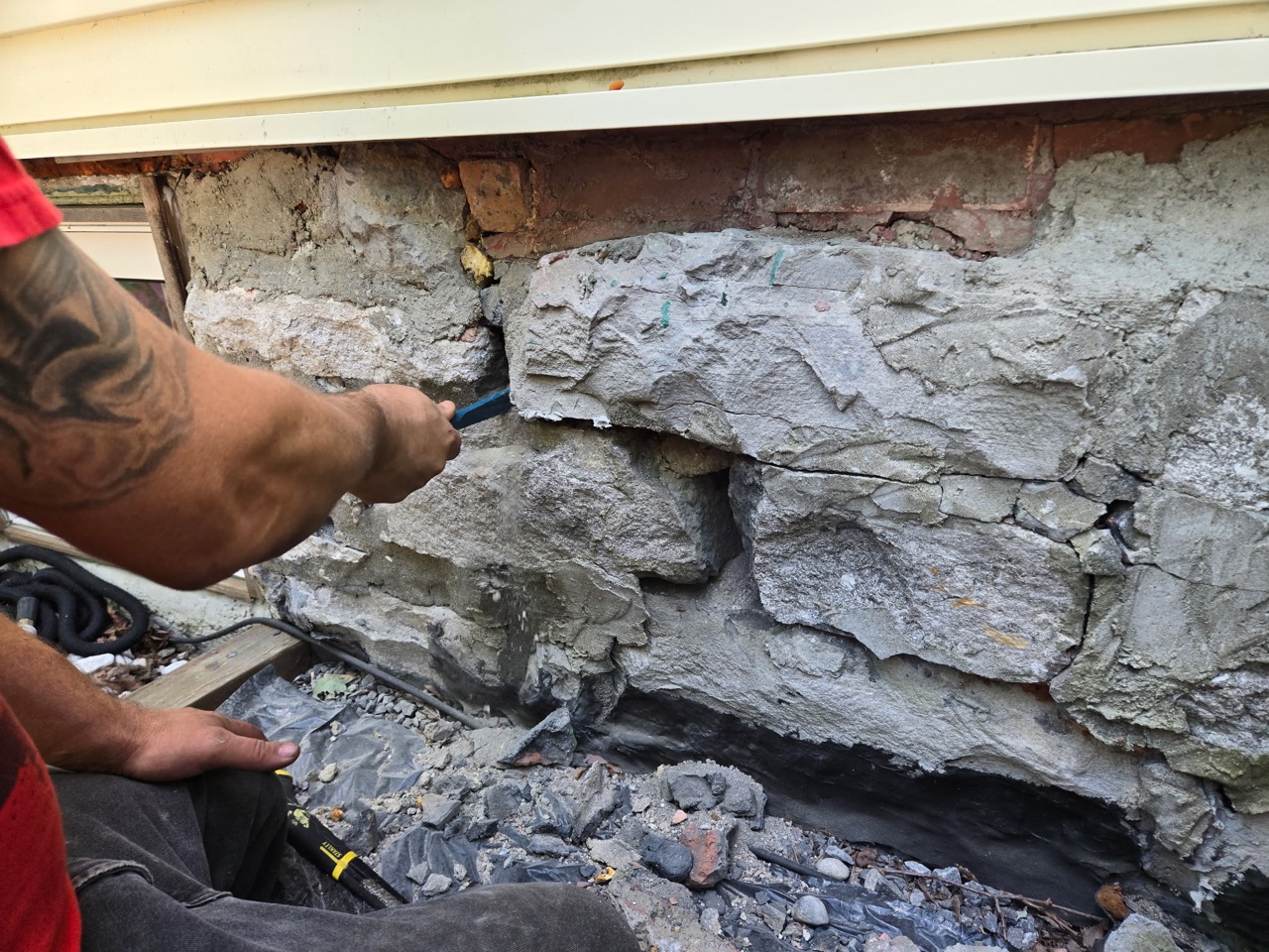 Close view of a worker repairing mortar joints in an exposed stone foundation